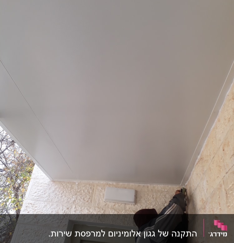 אדם מתקין תקרה מאלומיניום עם כלי עבודה